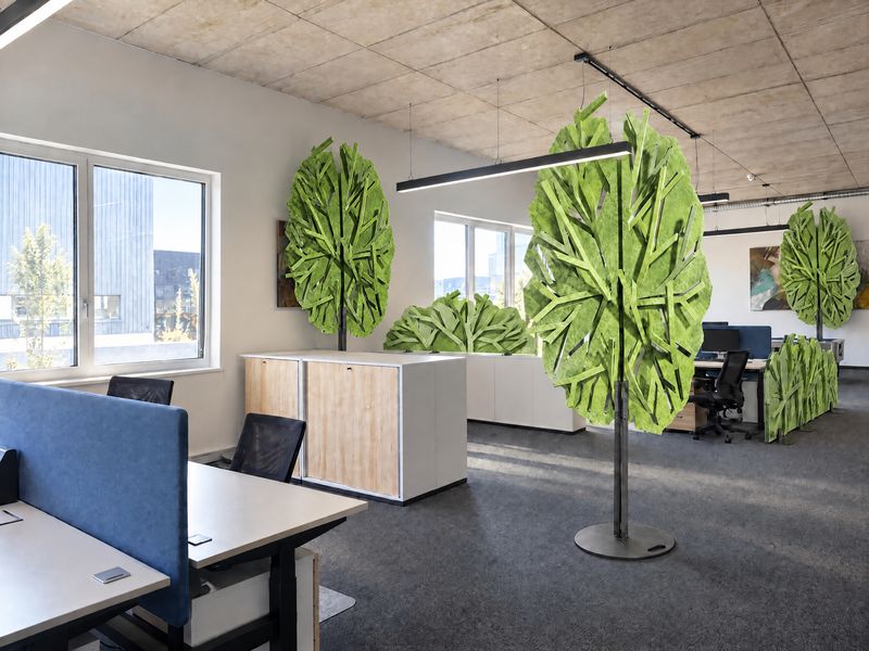 Drei grüne Bäume, ein Strauch auf einem Sideboard und eine Hecke an einem Doppeltisch in einem Büro